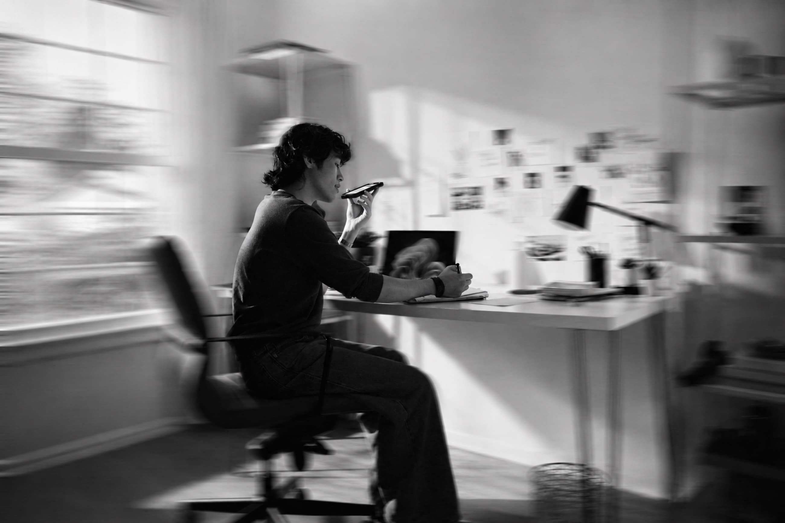 A person working at a desk while speaking into a phone.