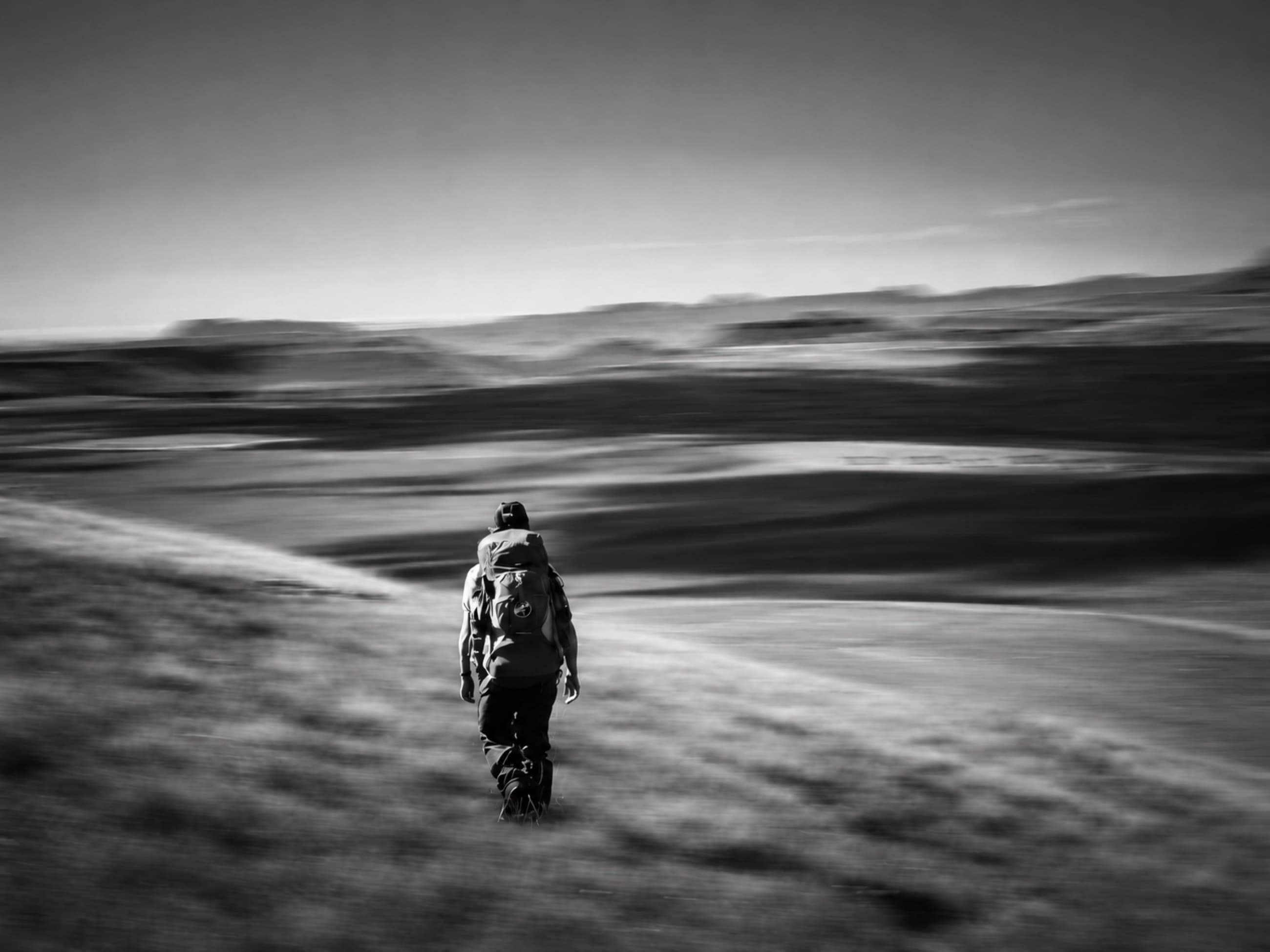 A person walking through an open black-and-white landscape.